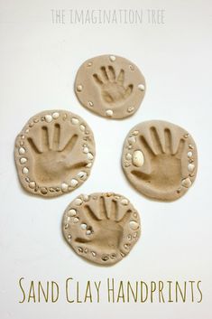 three clay handprinted magnets sitting on top of a white table next to each other