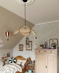 a bedroom with a bed, dresser and other items hanging from the ceiling above it