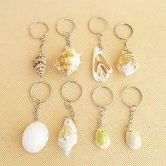 six seashell key chains are shown on a yellow surface