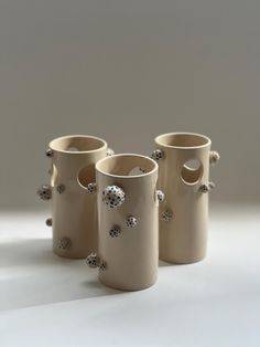 three white vases sitting next to each other on a table