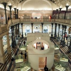 the inside of a museum with people looking at items in glass cases and on display