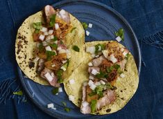 two tacos on a blue plate with onions and cilantro