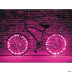 a bicycle is lit up with pink lights in front of a brick wall and floor