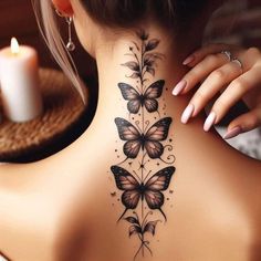 a woman's back neck with butterflies on it and a candle in the background