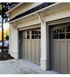 two garage doors are open in front of a white brick building