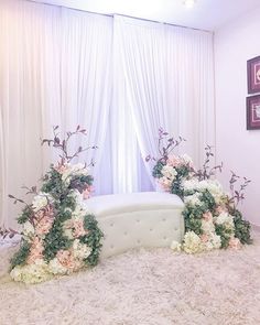 a white couch sitting in front of a window with flowers on the back and side