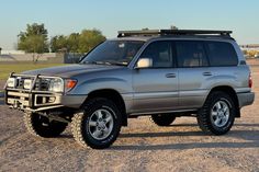 a silver suv parked on top of a dirt field