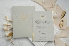 the wedding stationery is laid out on a white plate with gold foilwork and ribbon