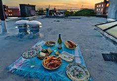 a picnic table with food and drinks on top of an old building in the evening