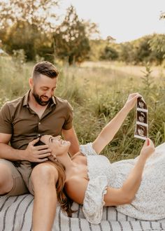 a man and woman laying on the ground holding an object in their hands while they look at each other