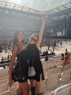 two women standing next to each other at a stadium