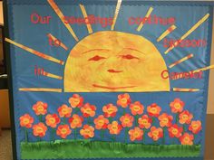 a bulletin board with flowers and the sun in the sky on it's side