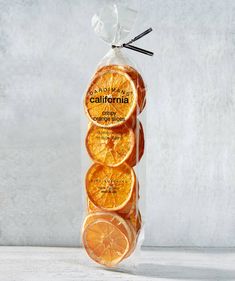 five orange slices in a cellophane bag on a white table with grey background