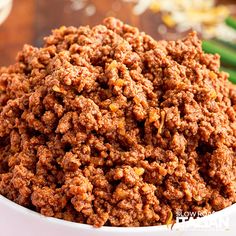 a close up of a bowl of food on a table with green beans in the background