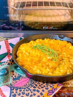 a pan filled with macaroni and cheese sitting in front of an open oven