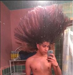 a shirtless man is taking a selfie in the bathroom with his hair blowing