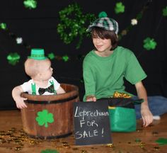 a baby sitting in a barrel next to a sign that says leprechaun for sale