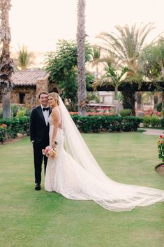 a bride and groom pose for a photo in front of palm trees at their wedding