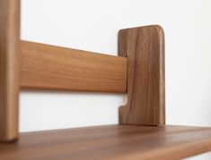 a close up of a wooden shelf against a white wall