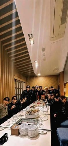 a group of people sitting at a long table with glasses on it and plates in front of them