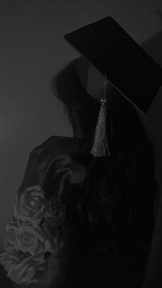 a woman with a graduation cap on her head holding a bouquet of flowers in front of her face