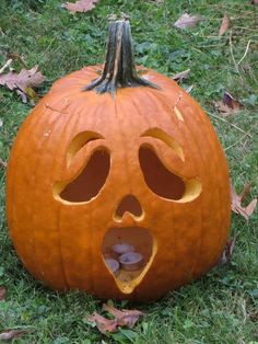 a carved pumpkin with its mouth open in the grass