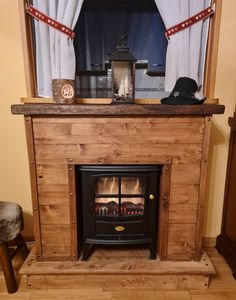 a wood burning fireplace in a living room next to a window with curtains on the windowsill