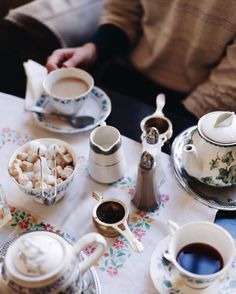 a table topped with tea cups and saucers filled with different types of food next to each other