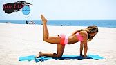 a woman is doing yoga on the beach with her feet in the air while flying a kite