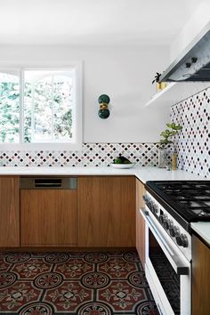 a kitchen with an oven, stove and counter top in the center is decorated with geometric tiles