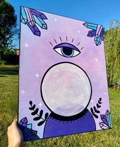 someone is holding up a purple painting with an eye and stars in the sky on it