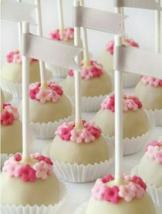 cake pops with pink and white sprinkles are arranged on a tray for display