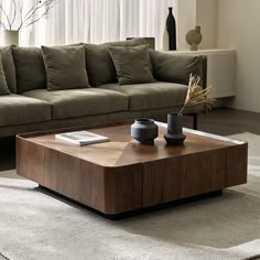 a living room with a couch, coffee table and vases on the carpeted floor