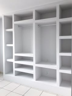 an empty room with white shelves and tile flooring