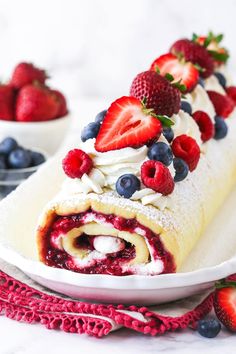 a pastry with strawberries and blueberries is on a plate next to some berries