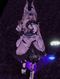 a woman dressed in white and black is standing next to a purple light with her hands up