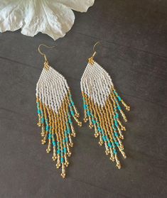 the beaded fringe earrings are hanging from gold - plated hooks with turquoise beads