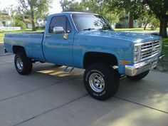 a blue pick up truck parked on top of a driveway