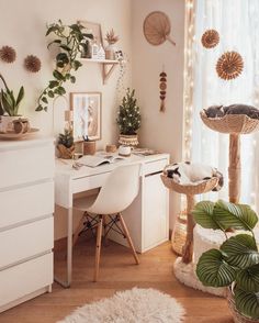 a white desk topped with a computer next to a window covered in lots of plants