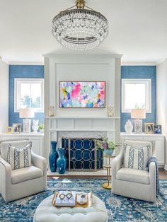 a living room filled with furniture and a chandelier above a fire place in front of a fireplace