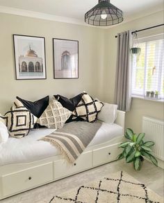 a living room with white couches and black and white pillows on top of them