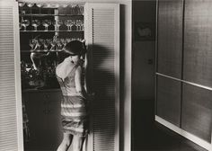 a woman standing in front of a wine rack with many glasses on it's shelves