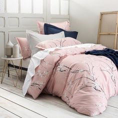 a bed with pink and blue comforters in a room next to a white wall