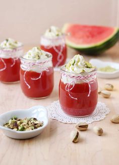 four jars filled with food sitting on top of a table next to watermelon slices