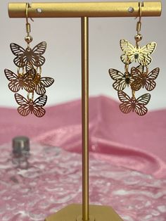 Filigree Butterfly Dangling Earrings in gold are delicately crafted, featuring intricate filigree work that forms the shape of elegant butterflies. These gold earrings offer a charming and whimsical touch, perfect for adding a subtle yet stylish statement to any outfit. Elegant Gold Butterfly Earrings, Elegant Gold Butterfly-shaped Earrings, Elegant Gold Earrings With Butterfly Charm, Gold Butterfly Metal Jewelry, Gold Butterfly-shaped Metal Jewelry, Delicate Gold Metal Earrings, Gold Butterfly Charm Earrings For Party, Gold Metal Earrings With Butterfly Charm, Gold Butterfly Earrings For Party