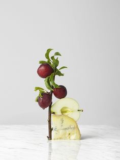 an apple and kiwi on a marble countertop with white walls in the background