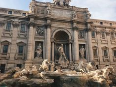 an ornate building with statues and fountains in front