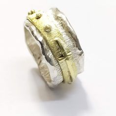 a gold and silver ring with a cross on the front, sitting on a white surface