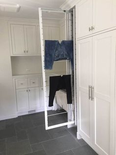 an open closet with clothes hanging from it's doors and cabinets in the background