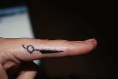 a person with a small tattoo on their finger pointing to the left side of her finger